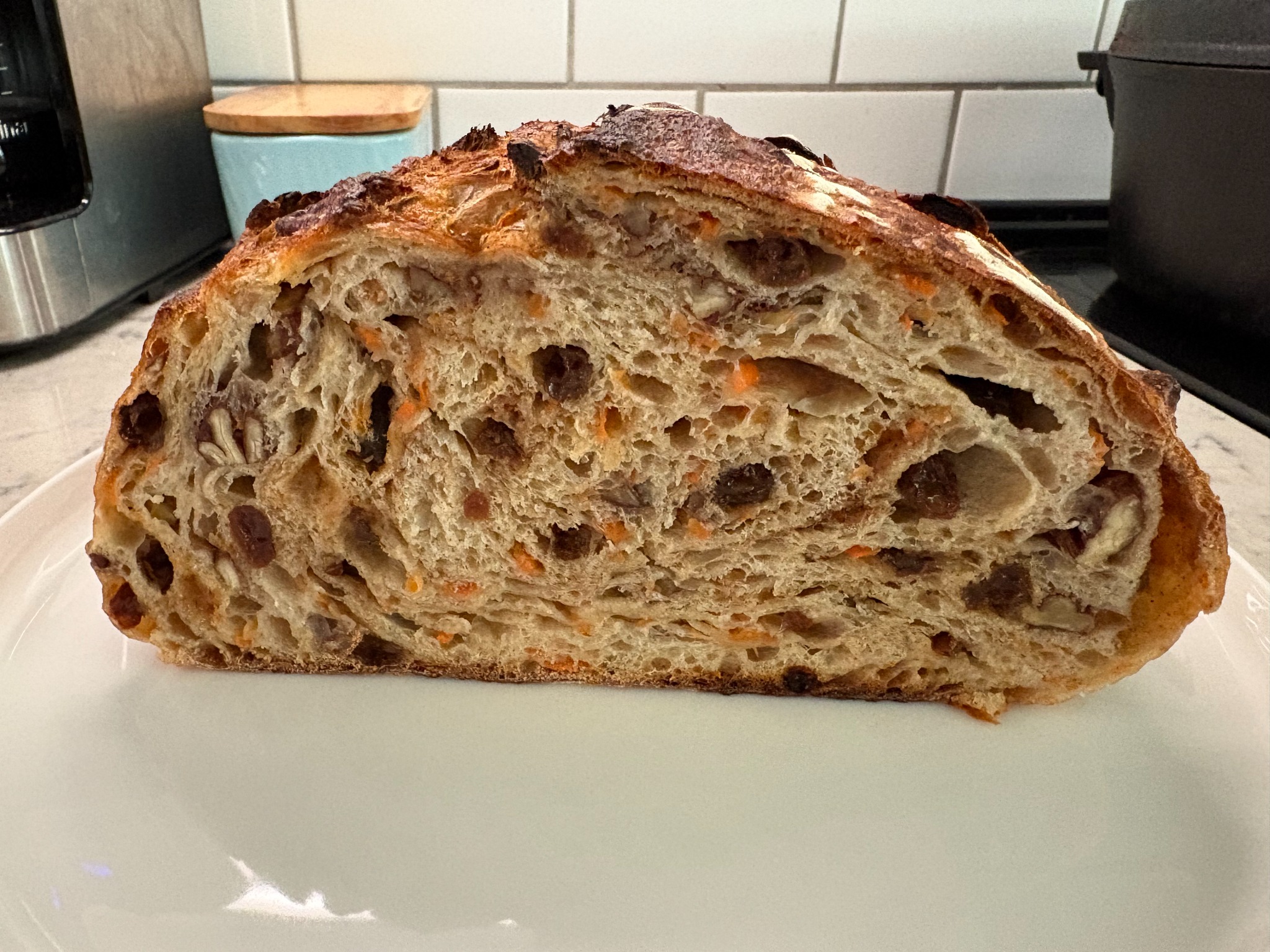 A sliced carrot cake sourdough loaf showing shredded carrots, raisins, and pecans in the crumb