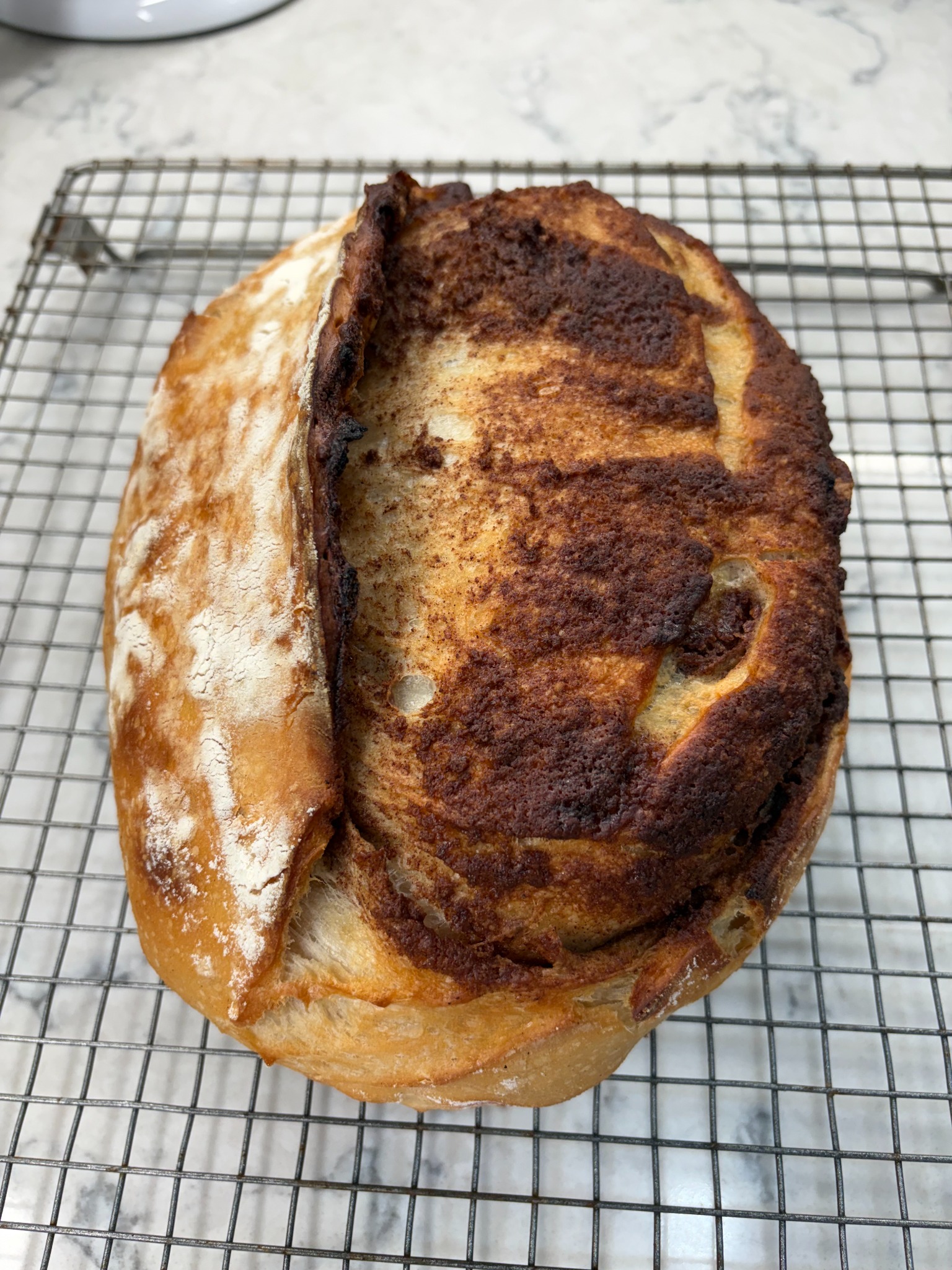 Lori’s cinnamon sourdough bread cooling on a wire rack, with a golden crust and cinnamon swirl.